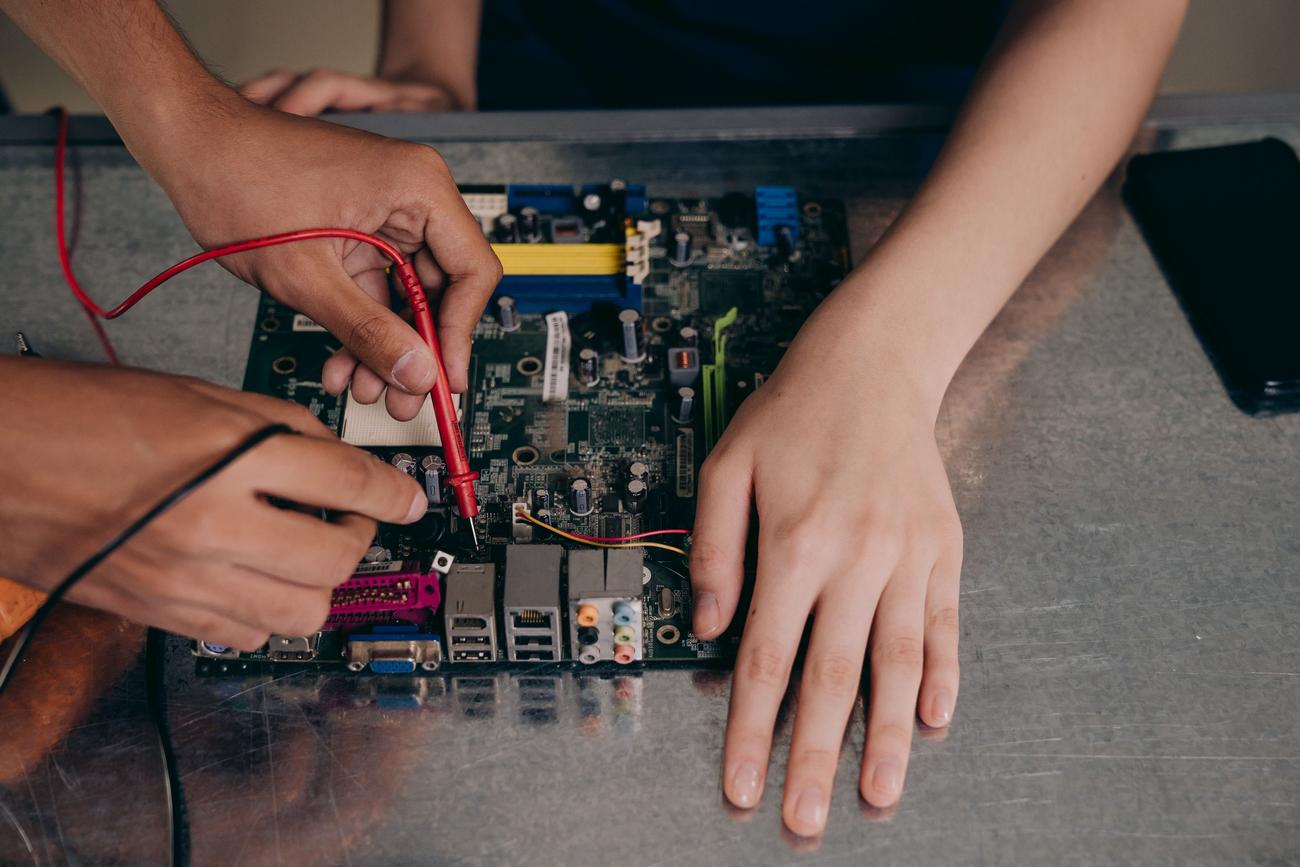 Técnico utilizando una herramienta de medición en una placa base para realizar una auditoría de hardware profesional.