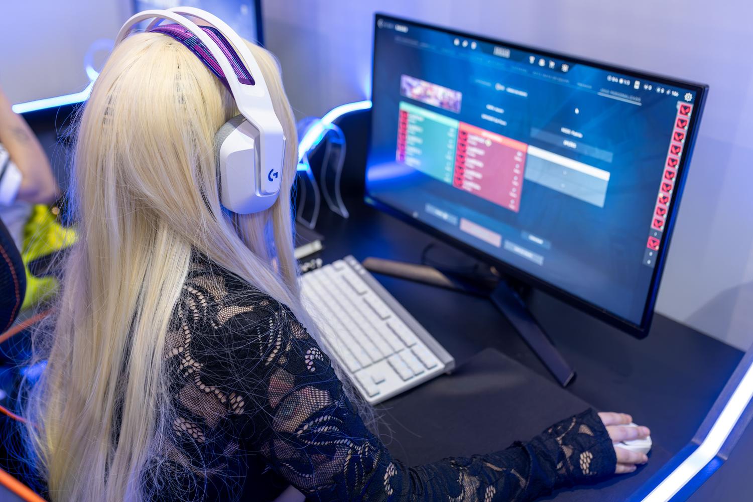 Mujer configurando el software de sus periféricos gaming en un monitor, ilustrando la personalización de perfiles de audio y ajustes de software.
