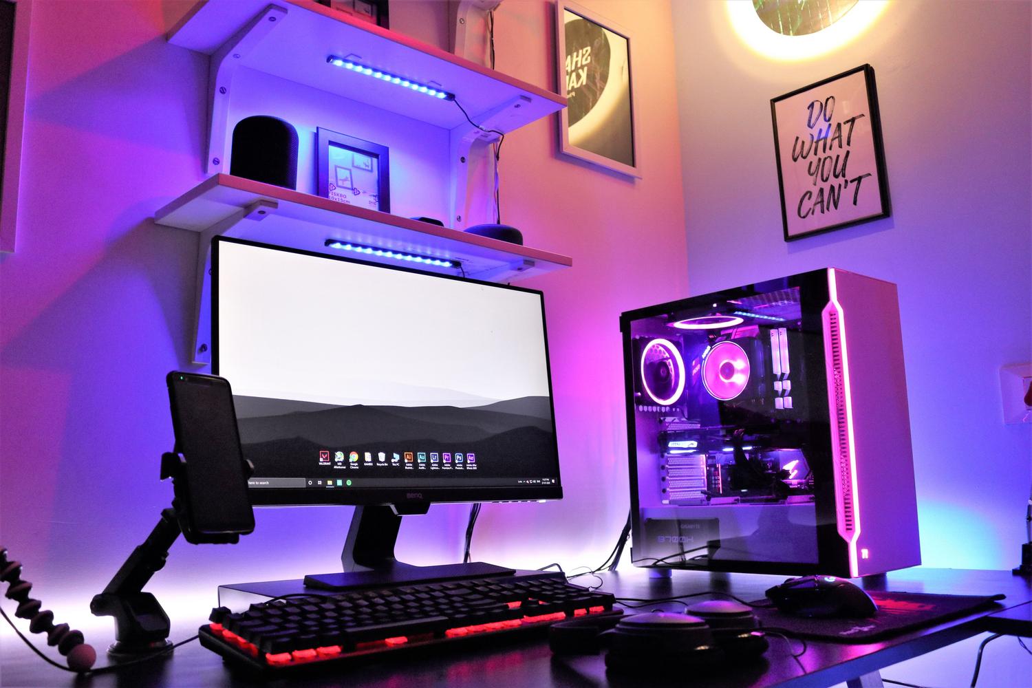 Setup gaming completo con iluminación RGB sincronizada en tonos púrpuras y azules, mostrando la estética y el control de iluminación del ecosistema gaming.