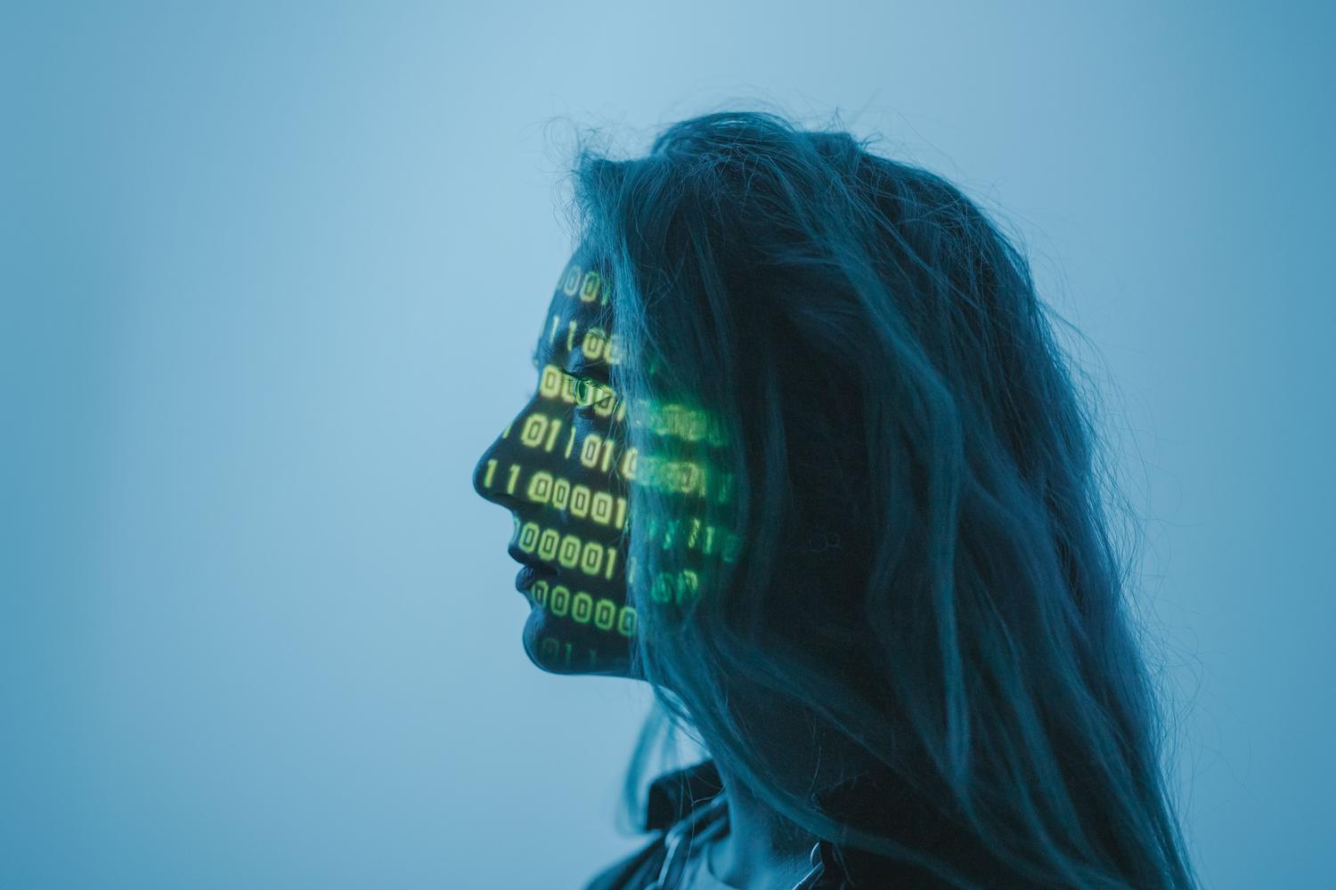 Perfil humano con proyección de código binario verde, ilustrando la privacidad de datos, la ciberseguridad y la fusión humano-máquina.