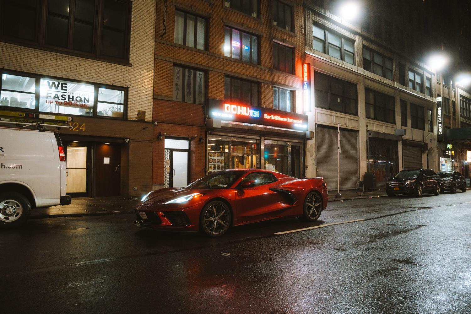 Coche deportivo rojo estacionado en una calle urbana nocturna, resaltando la estética y personalización vehicular.