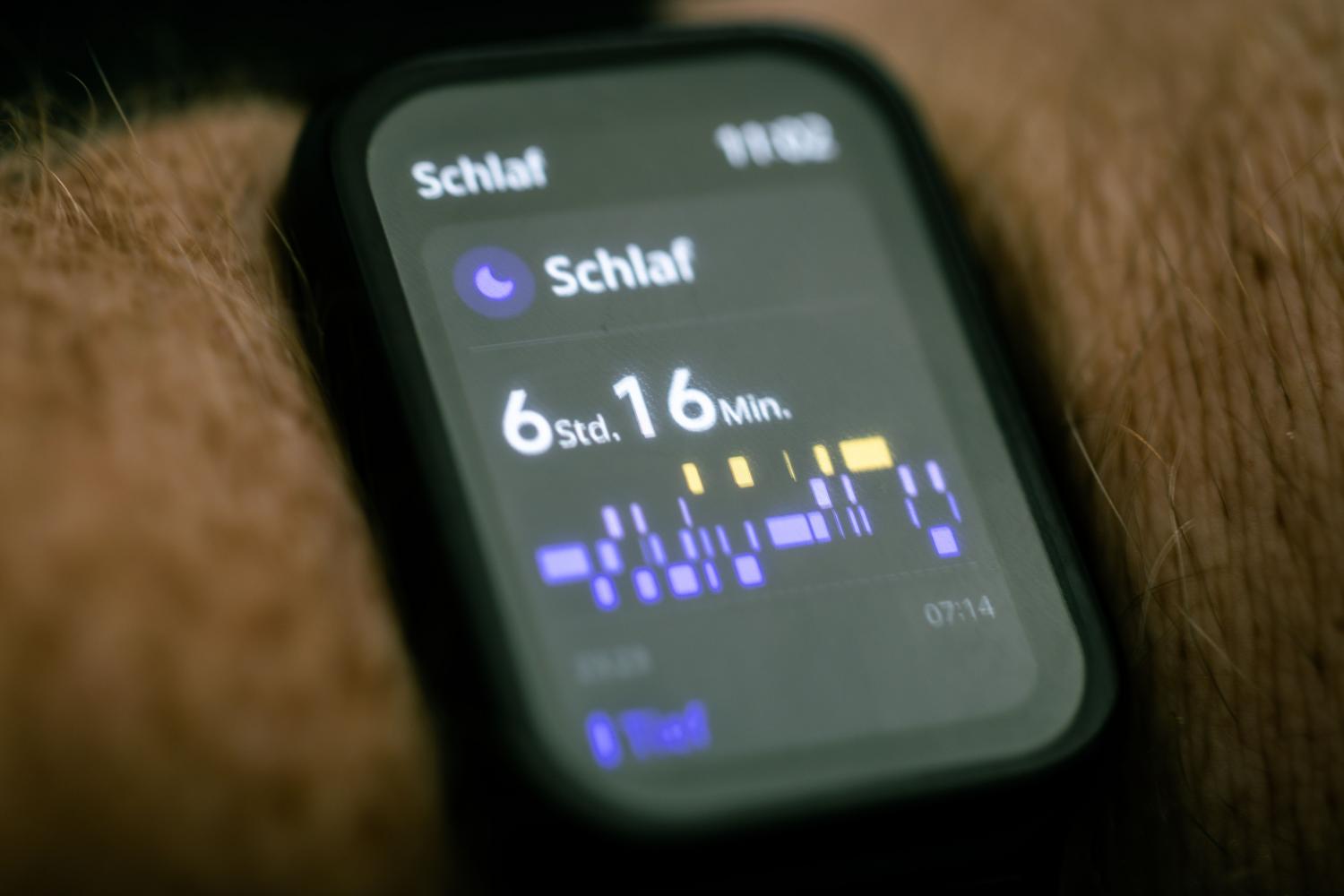 Detalle de la pantalla de un reloj inteligente mostrando datos y gráficas de seguimiento del sueño.