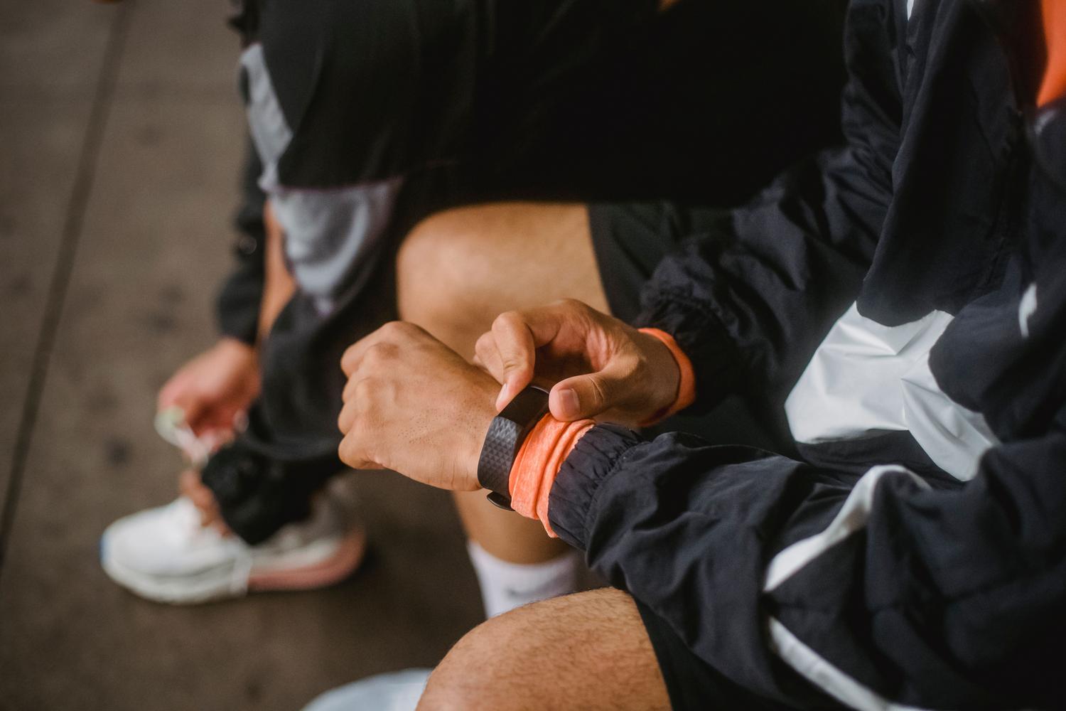 Hombre con ropa deportiva ajustando su reloj inteligente antes de comenzar una rutina de ejercicio al aire libre.