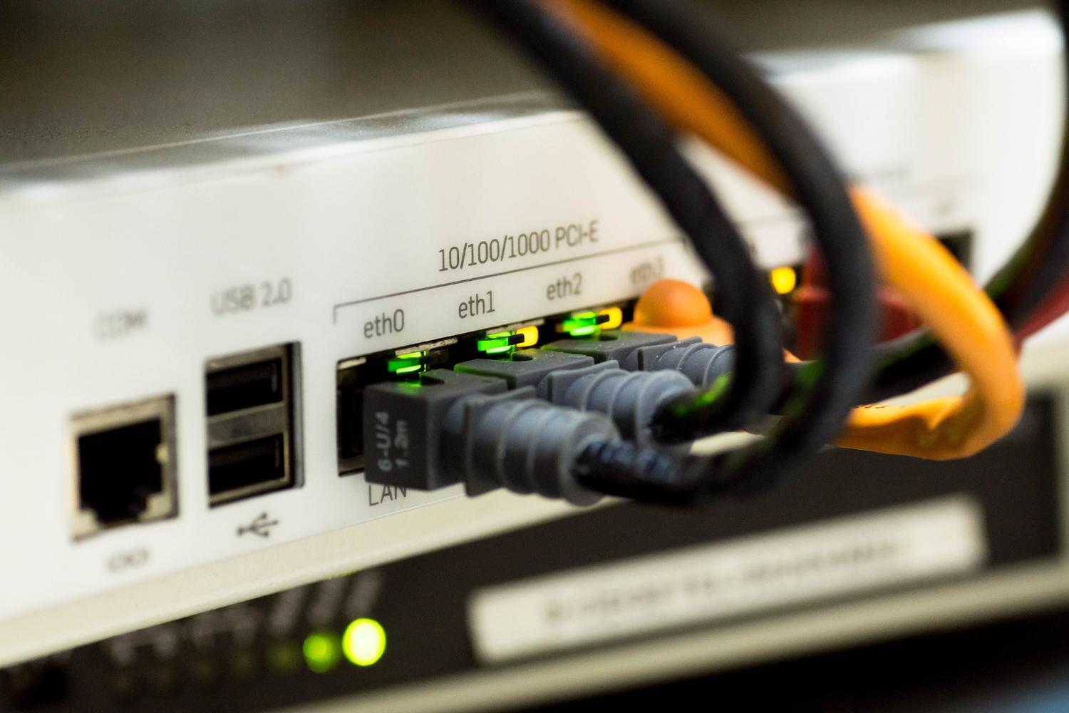 Primer plano de cables Ethernet y conectores de red en un router, representando la infraestructura física y cables Cat 6a/7 necesarios.