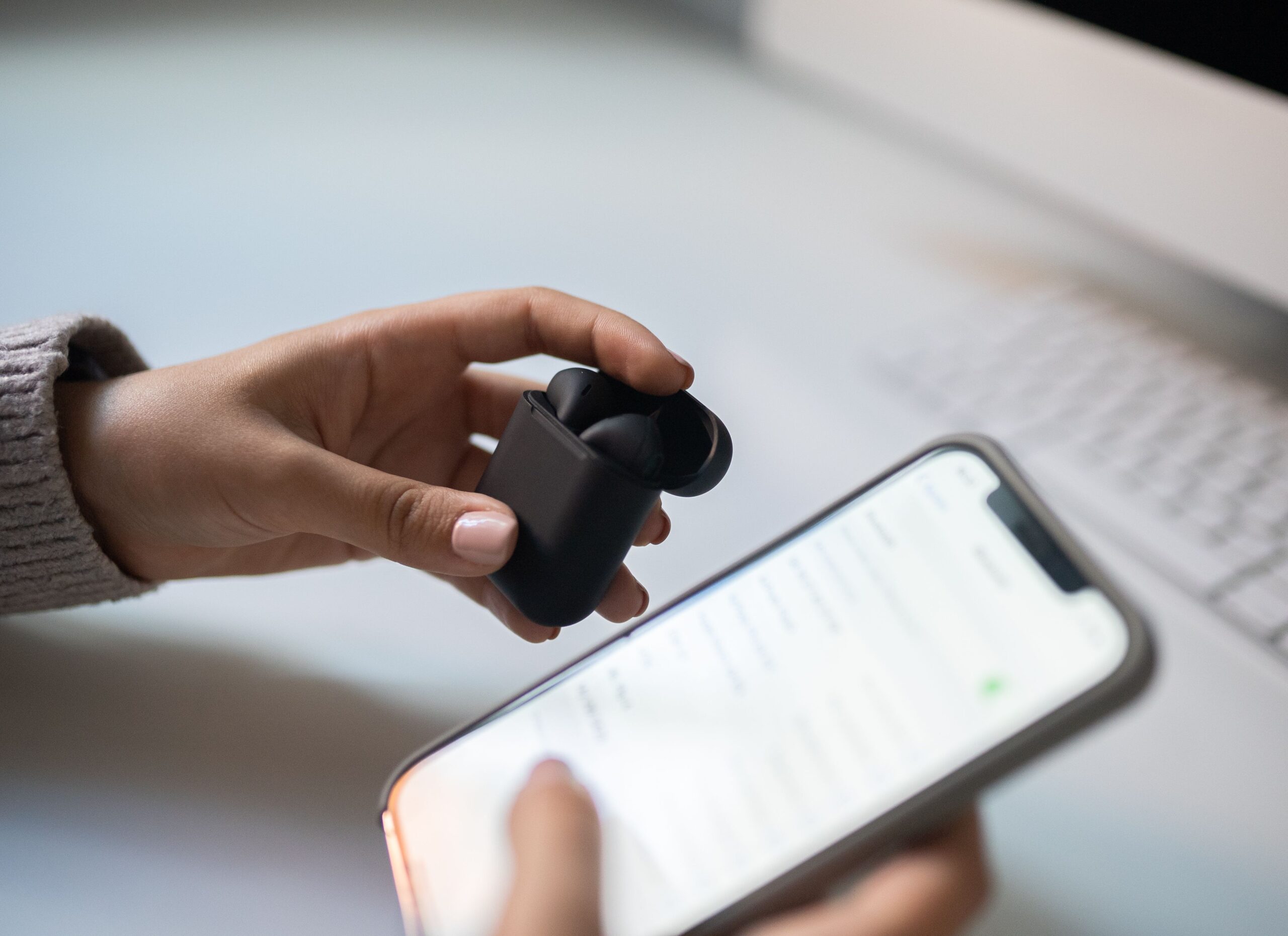 Primer plano de unas manos emparejando auriculares inalámbricos con la pantalla de un smartphone, ilustrando el proceso de configuración y conectividad.