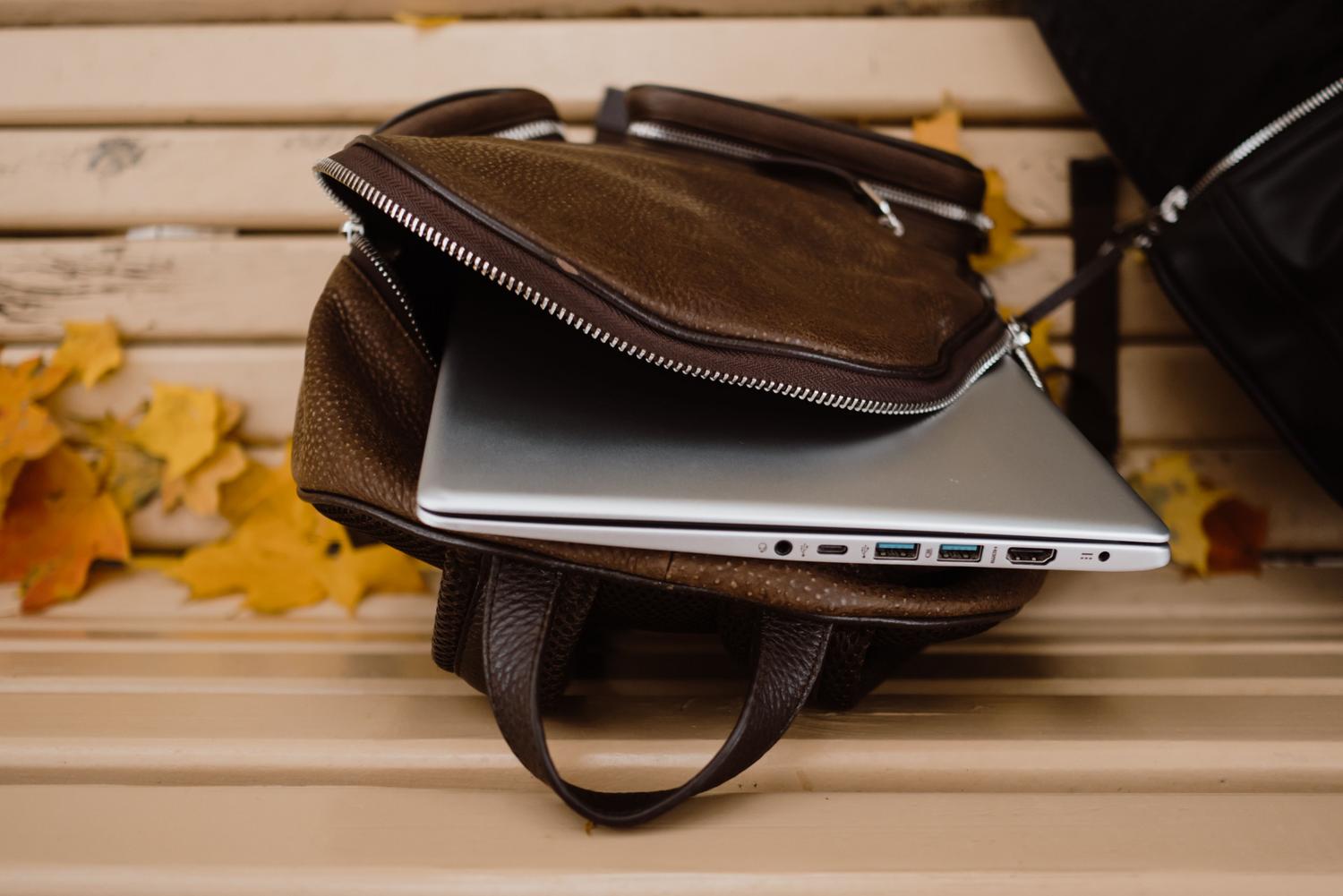 Ultrabook guardado en una mochila de cuero, representando la movilidad absoluta y el transporte cómodo.