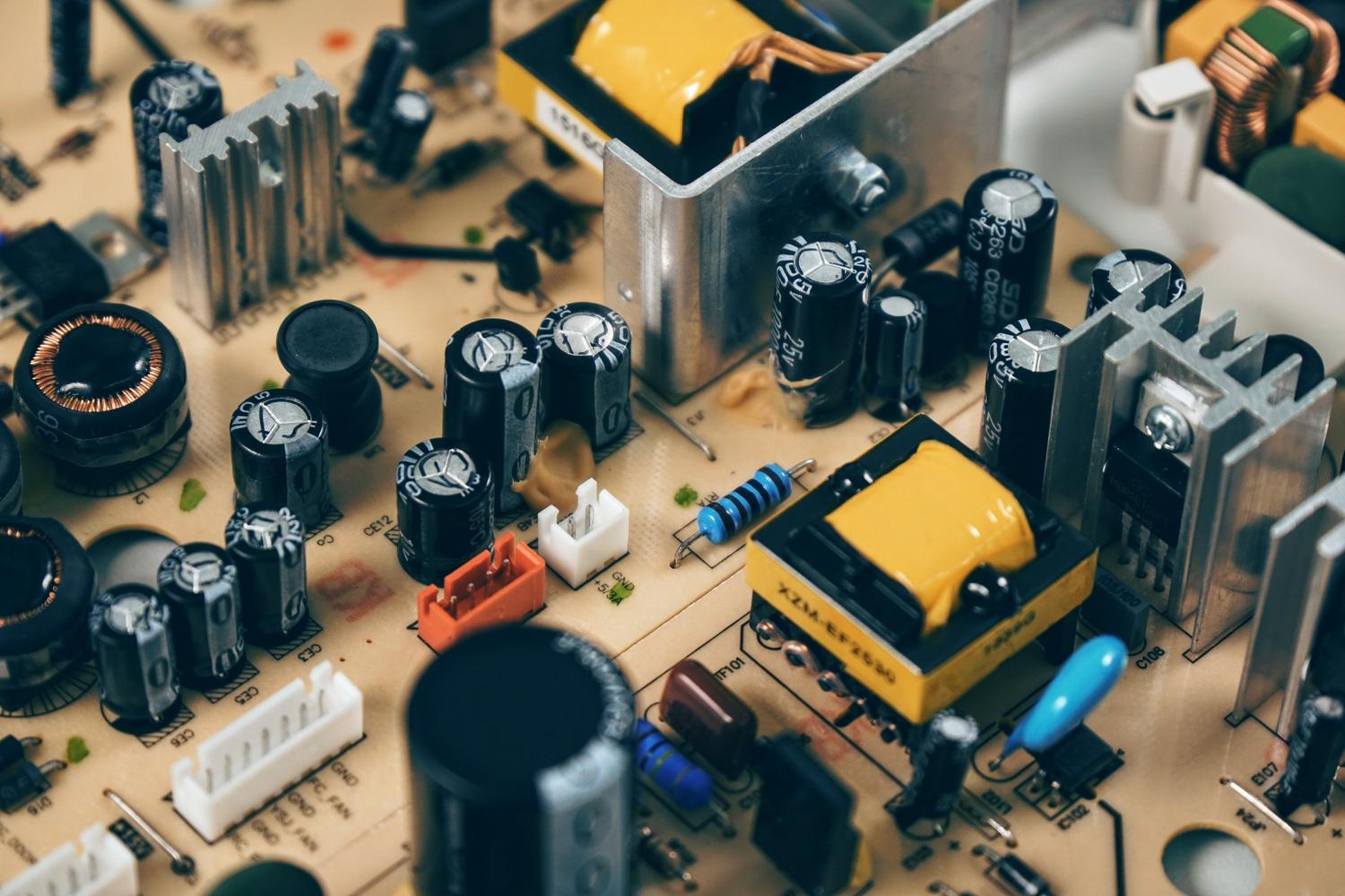 Primer plano detallado de condensadores y resistencias en una placa de circuito impreso, representando los componentes básicos de la electrónica.