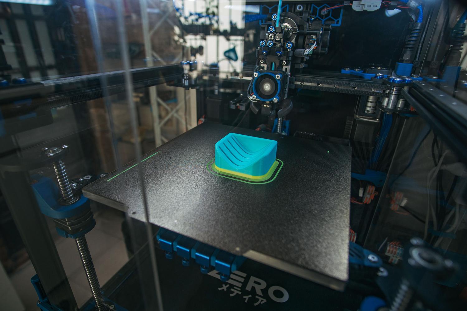 Detalle de una boquilla de impresora 3D industrial creando una pieza plástica con alta precisión.