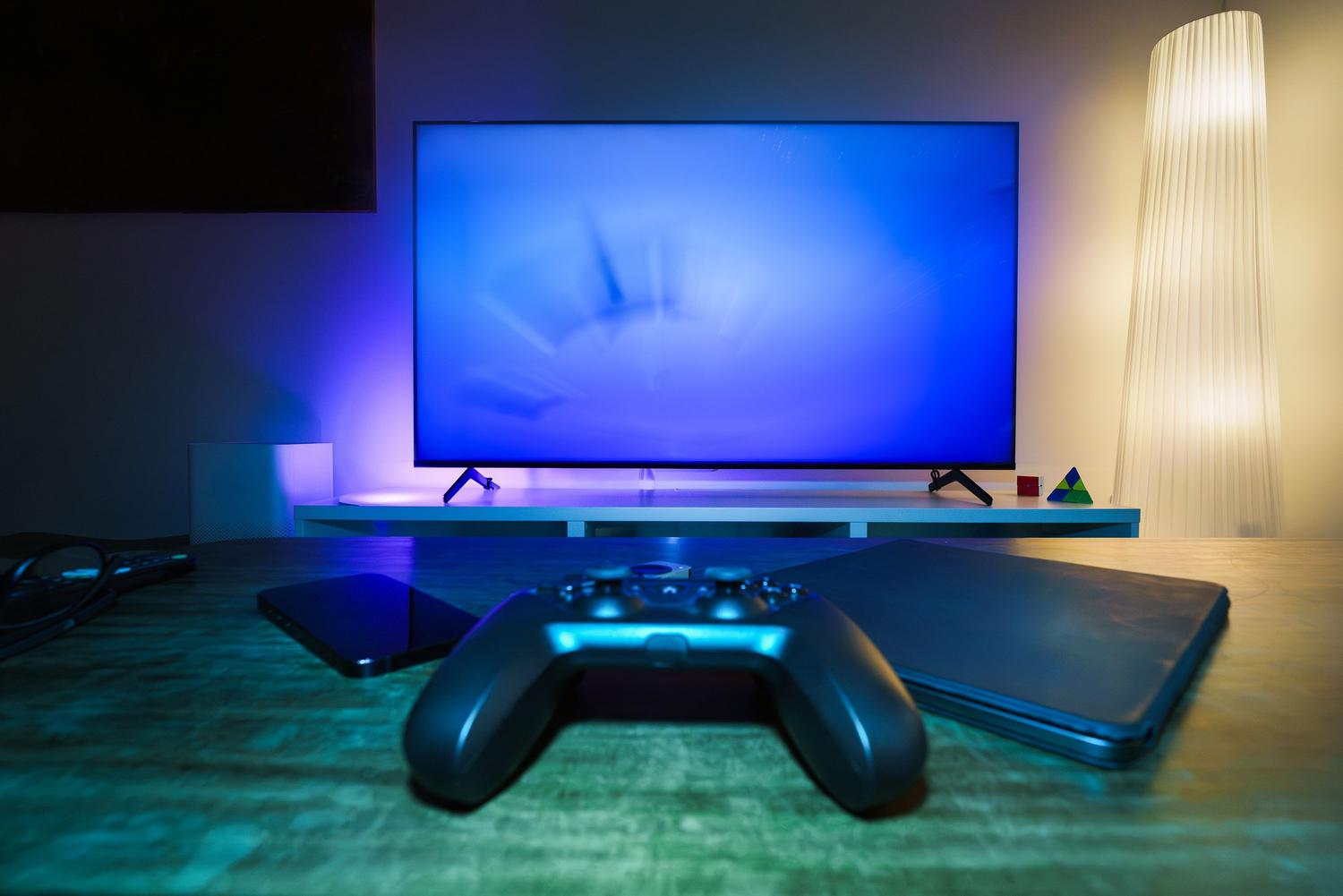 Configuración de gaming avanzada con televisor inteligente, consola y ambiente con iluminación LED azul.