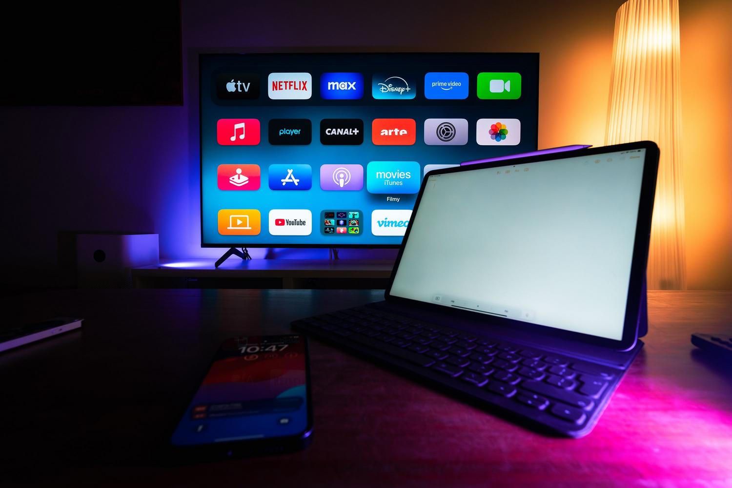 Ecosistema de hogar inteligente con televisor, tablet y smartphone integrados en un entorno moderno.