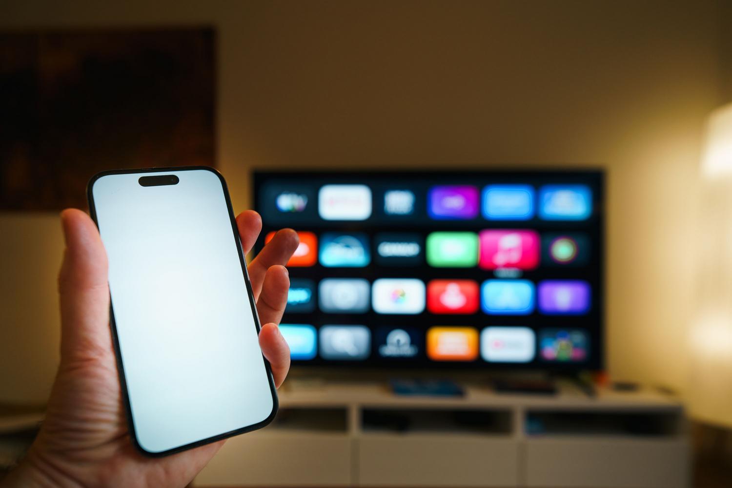 Uso de un smartphone para controlar las funciones de un televisor inteligente en un salón acogedor.