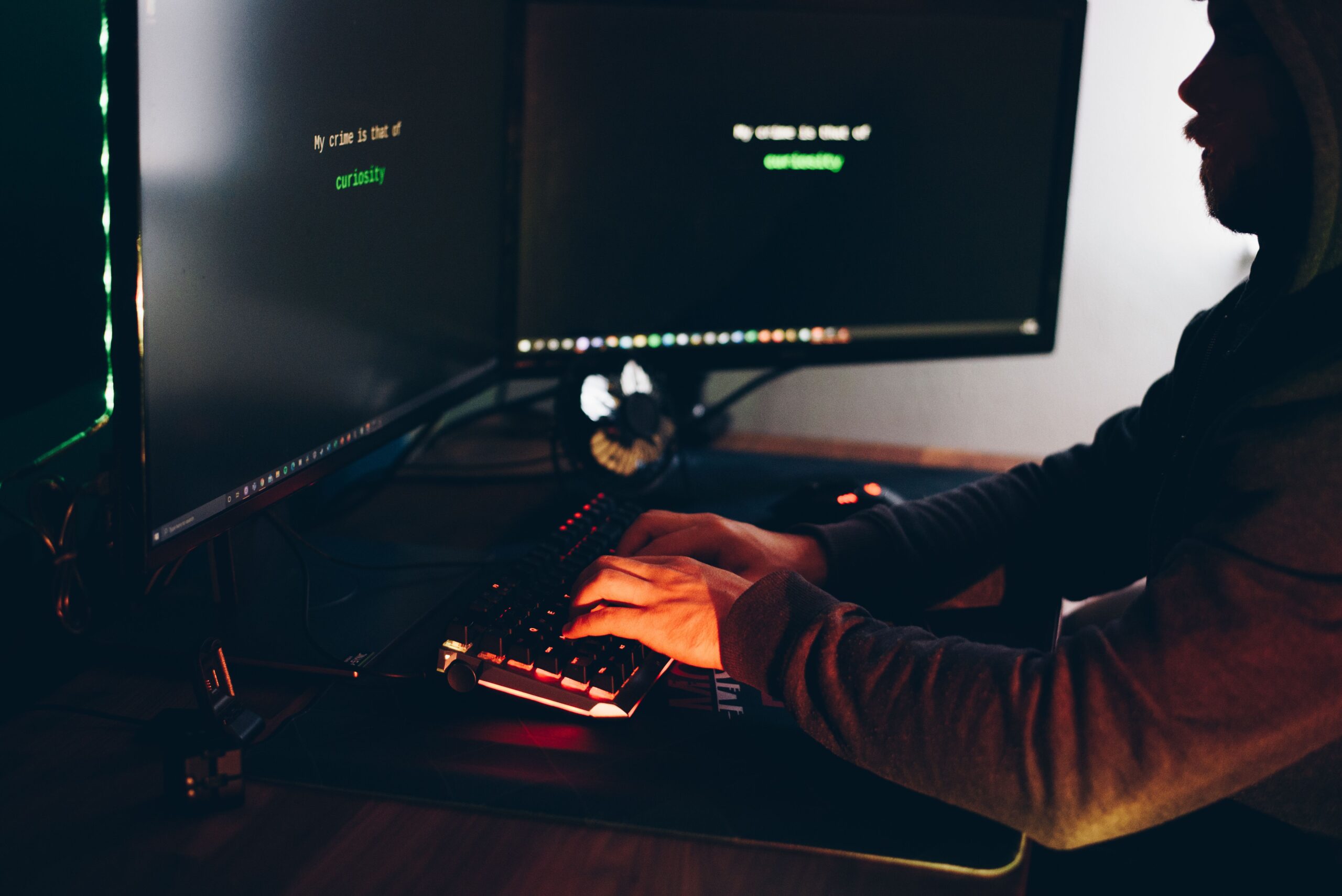 Silueta de un hacker escribiendo en un teclado iluminado en rojo, representando la amenaza de los ciberataques.