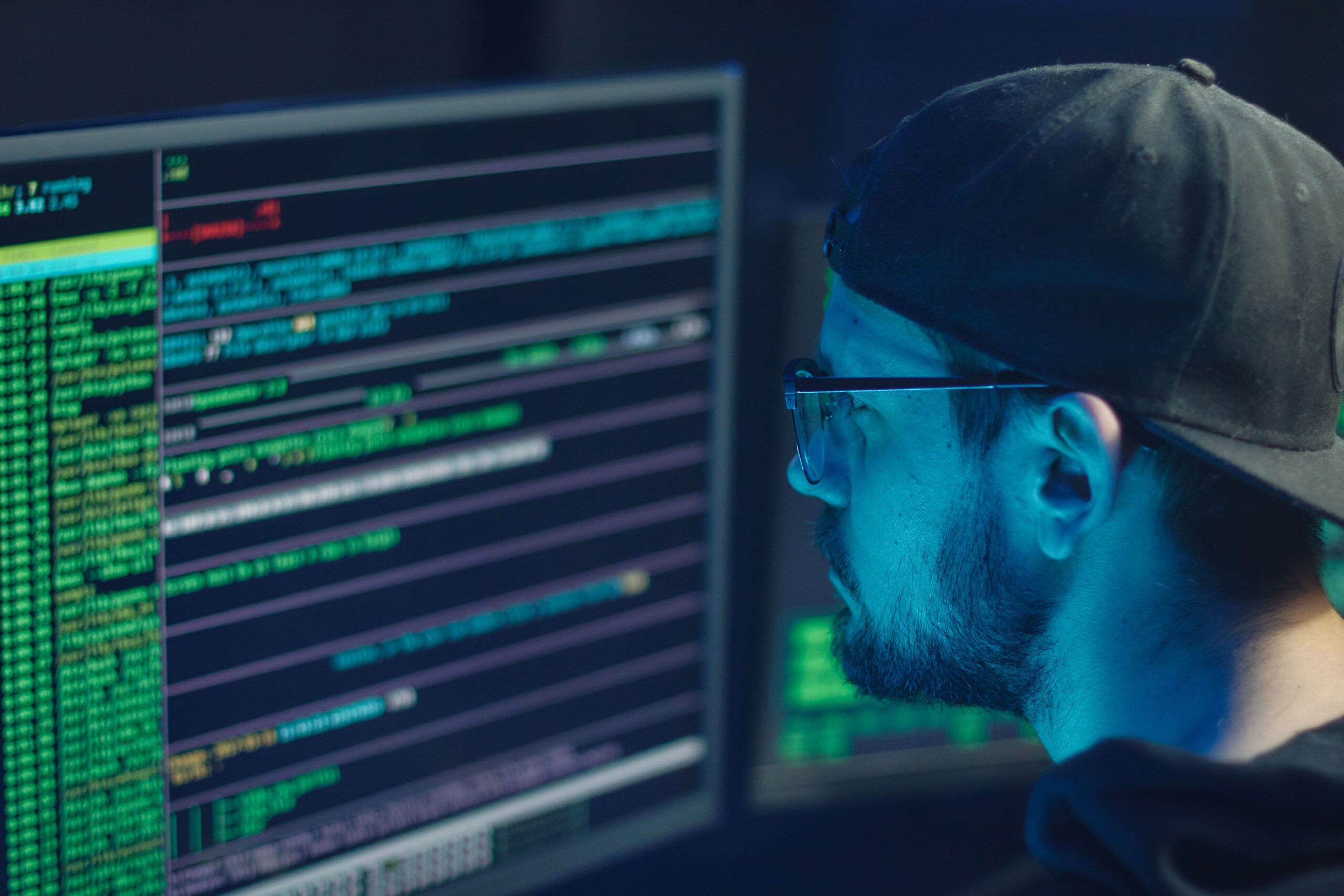 Experto en ciberseguridad analizando líneas de código en múltiples monitores para detectar amenazas.