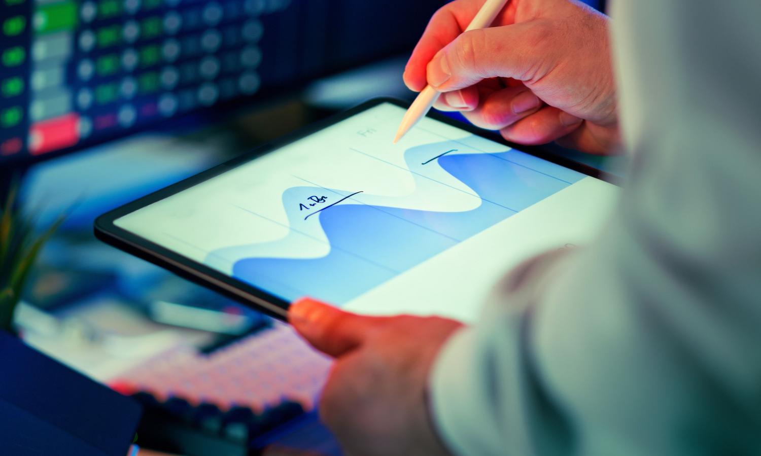 Profesional analizando un gráfico de datos en una tablet con un lápiz óptico, representando la capacidad de análisis y extracción de datos mediante IA.