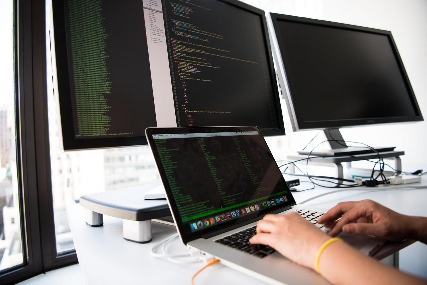 Entorno de trabajo de un desarrollador con múltiples monitores y una terminal de comandos abierta para automatización de scripts.
