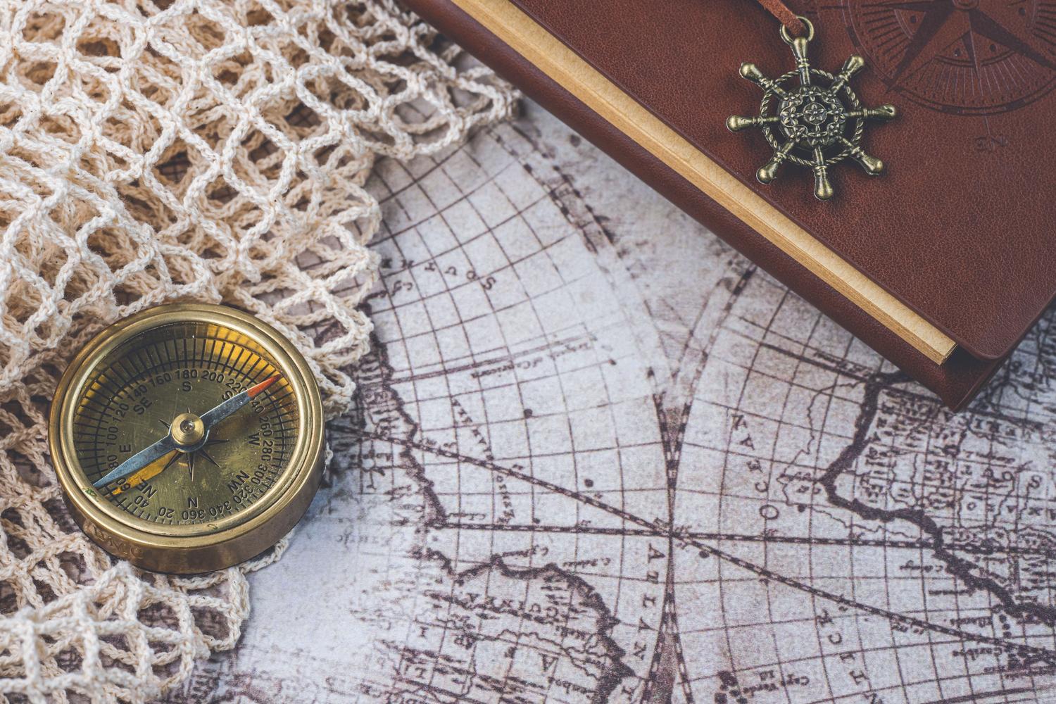 Brújula antigua y cuaderno sobre un mapa retro, ilustrando la mecánica de navegación y supervivencia.