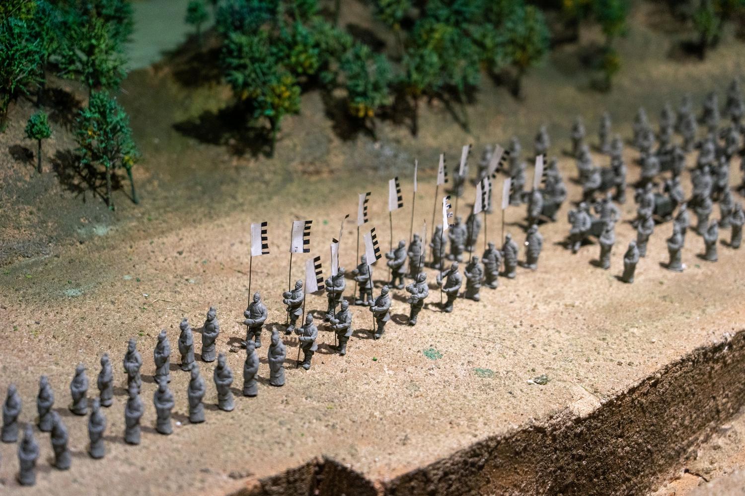 Miniaturas de un ejército en formación táctica sobre un mapa, ilustrando la estrategia por turnos del título.