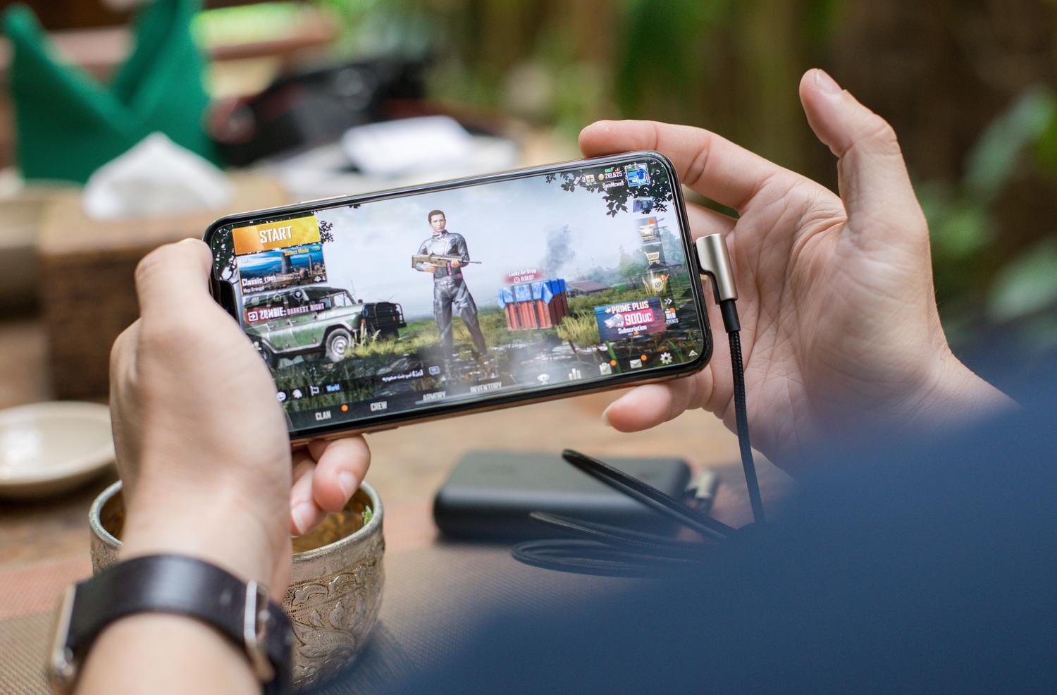 Usuario jugando a un videojuego competitivo en el móvil, donde una tasa de refresco alta minimiza el desenfoque de movimiento.