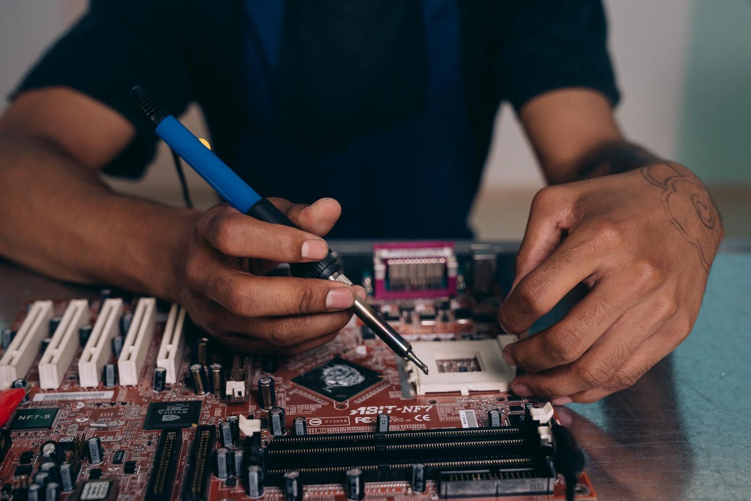 Técnico realizando soldaduras de precisión en una placa base para asegurar la integridad física de los conectores.
