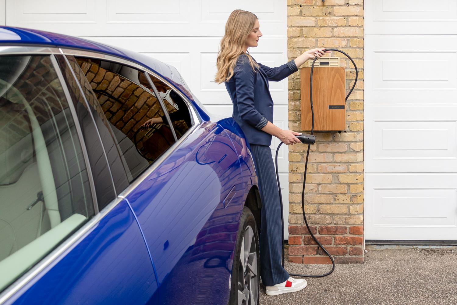 Carga de un vehículo eléctrico en un punto de recarga doméstico en el garaje de una casa.