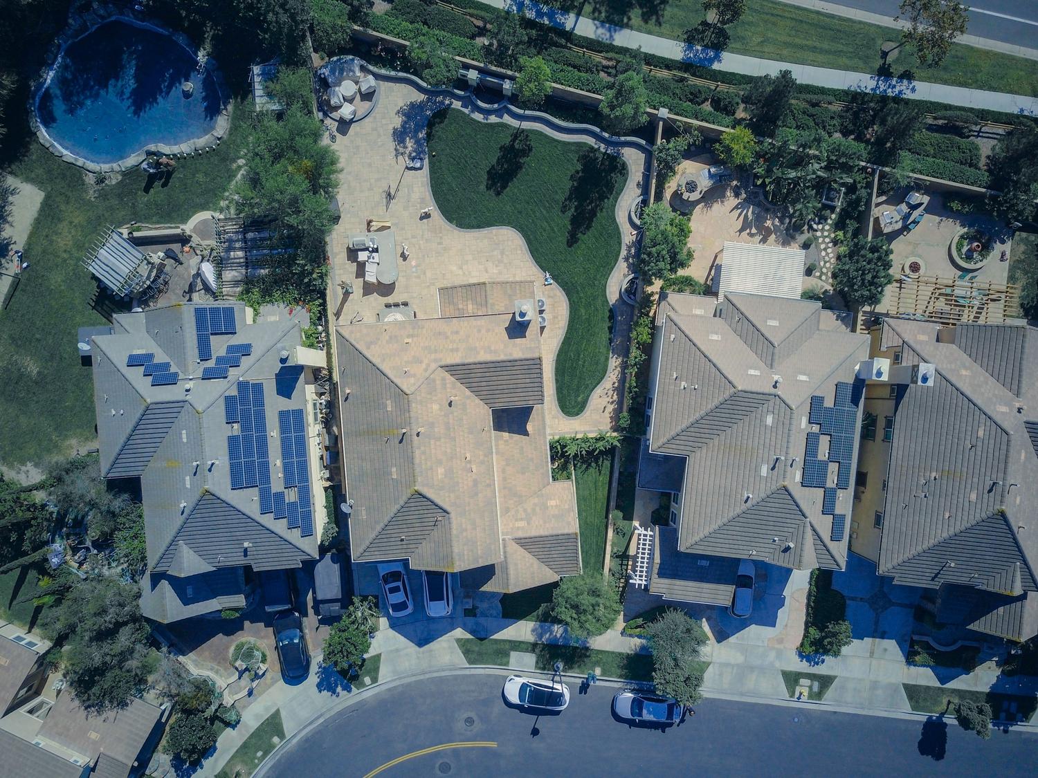 Vista aérea de un barrio residencial con tejados equipados con placas solares, representando un ecosistema energético sostenible.