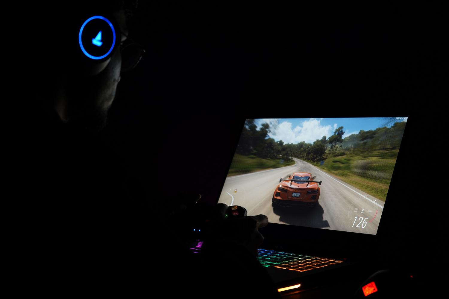 Un gamer utilizando un portátil y auriculares en un entorno oscuro, ilustrando el rendimiento en juegos