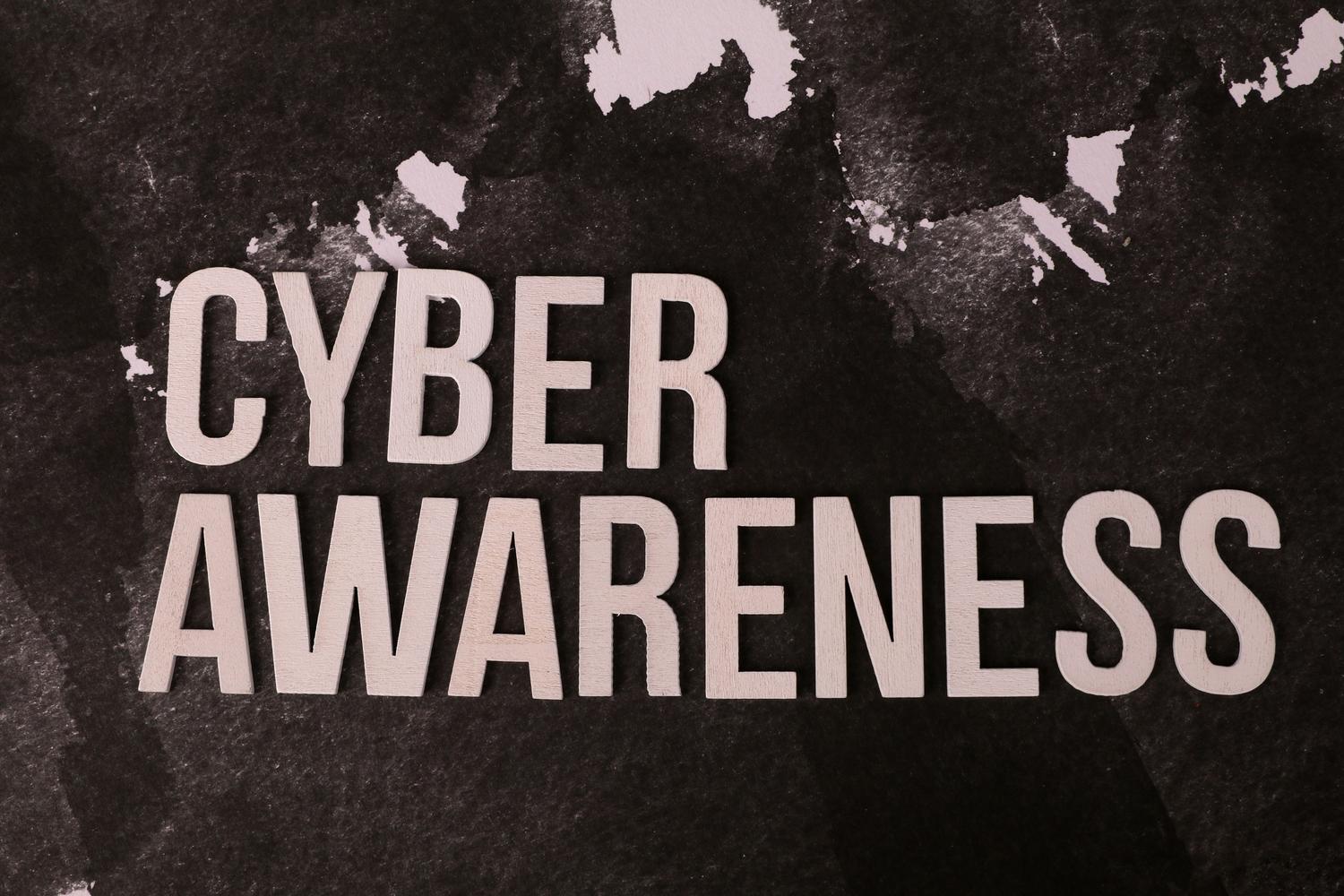 Letras en relieve que forman la frase 'Cyber Awareness' sobre un fondo oscuro y texturizado, simbolizando la concienciación en ciberseguridad.