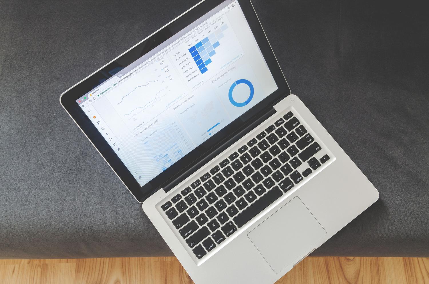 Vista cenital de un portátil mostrando cuadros de mando de análisis de datos y gráficos, simbolizando la optimización y gestión de costes cloud.