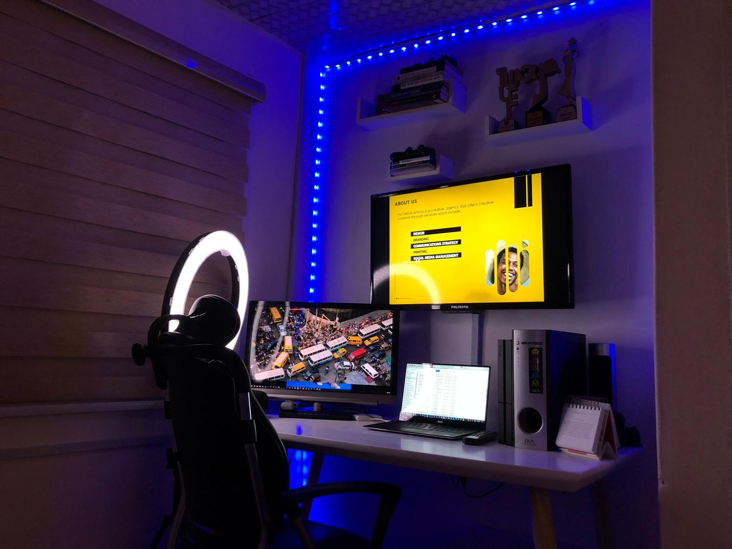 Configuración de oficina en casa con múltiples monitores e iluminación ambiental, representando la gestión de pantallas en entornos de productividad.