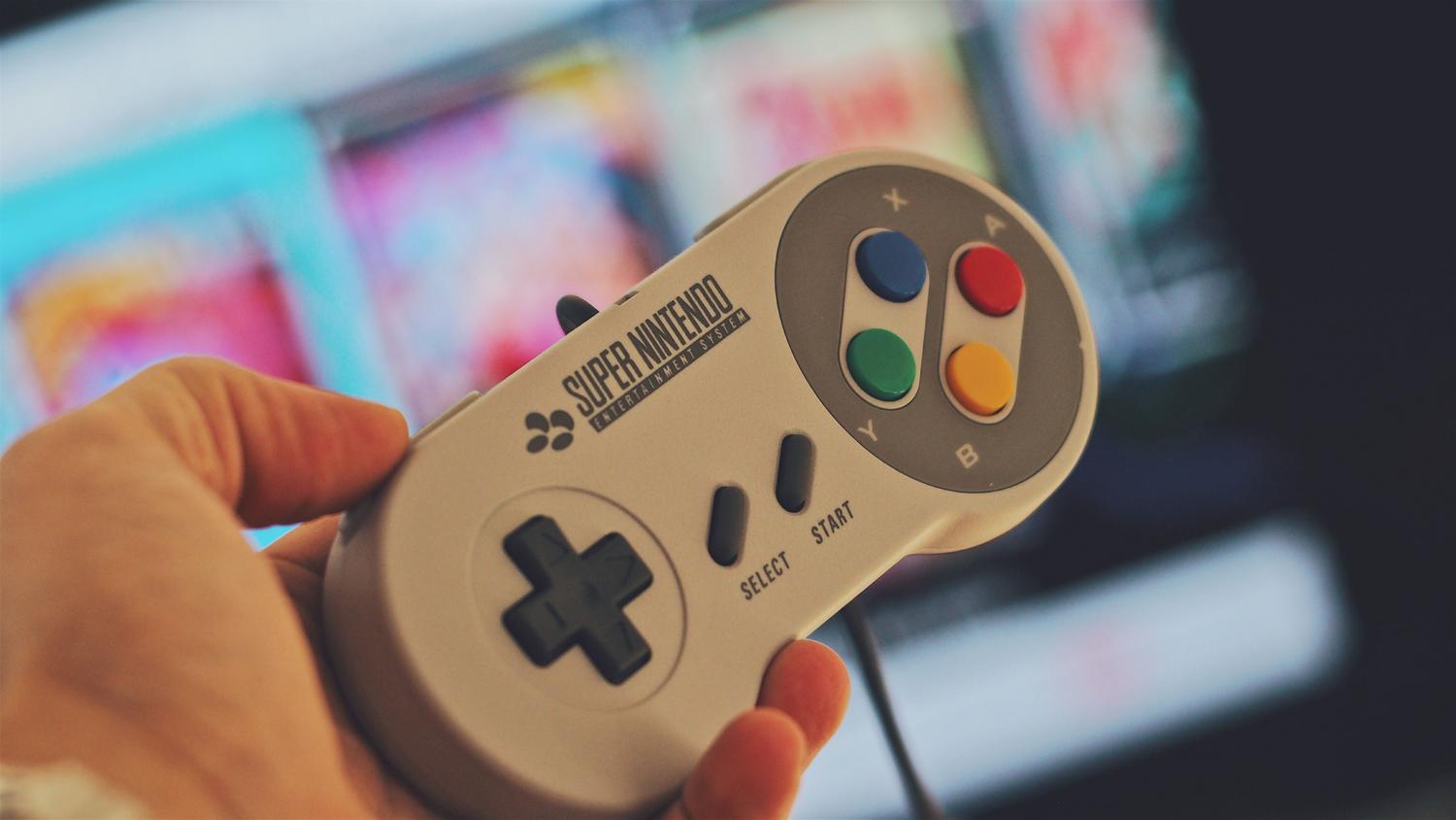 Mano sosteniendo un mando clásico de Super Nintendo (SNES) con la cruceta característica.