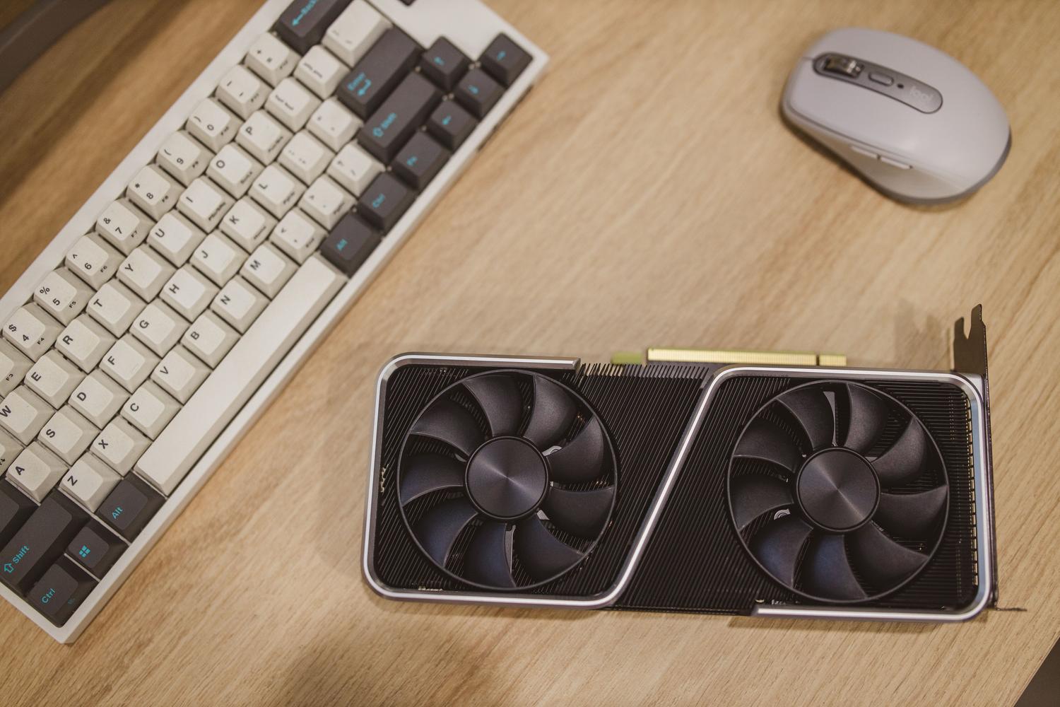 Tarjeta gráfica sobre un escritorio junto a un teclado y un ratón, proporcionando un contexto de hardware para el consumidor.