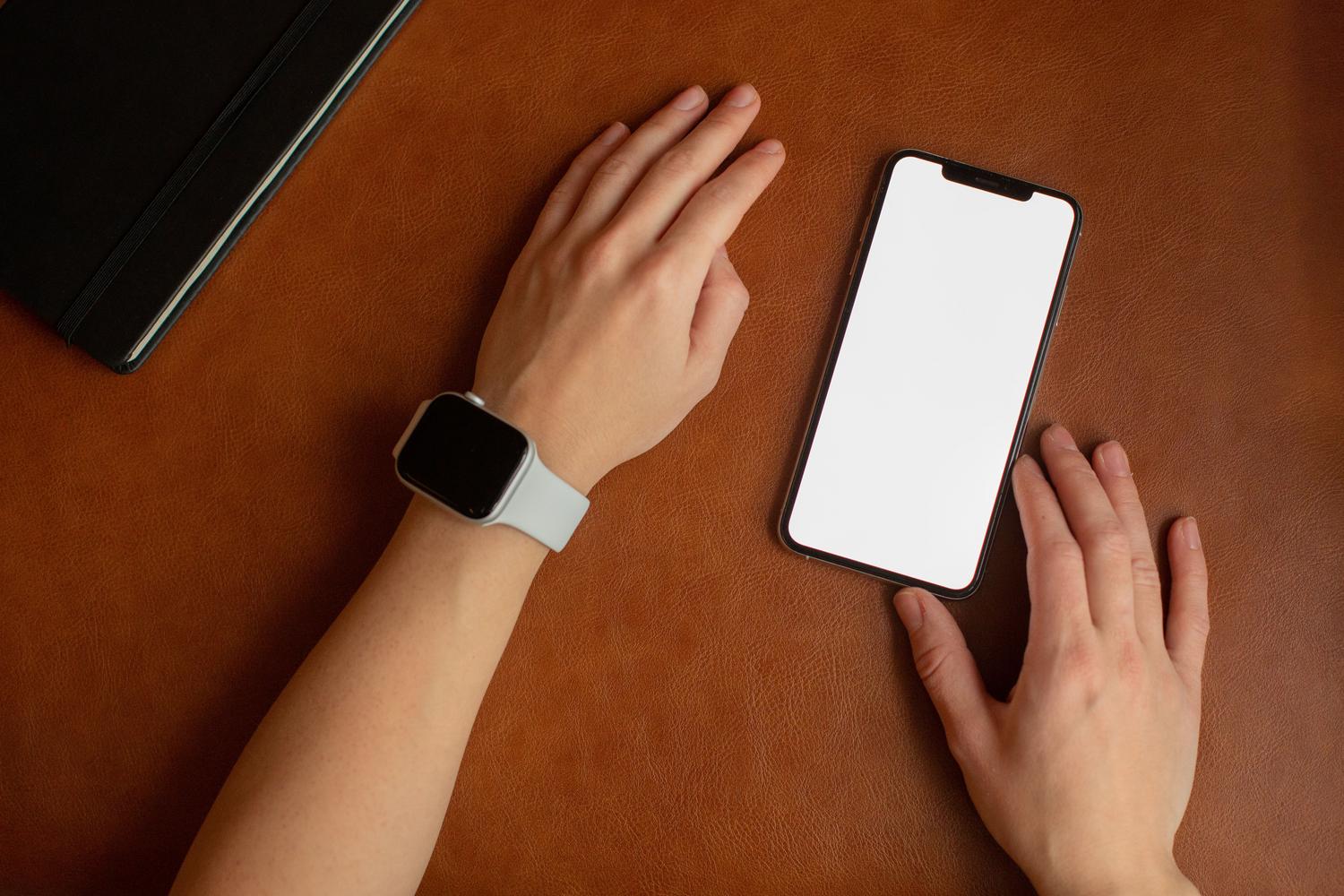 Smartphone y smartwatch juntos sobre una superficie de cuero, representando el desbloqueo automático por dispositivos vinculados.