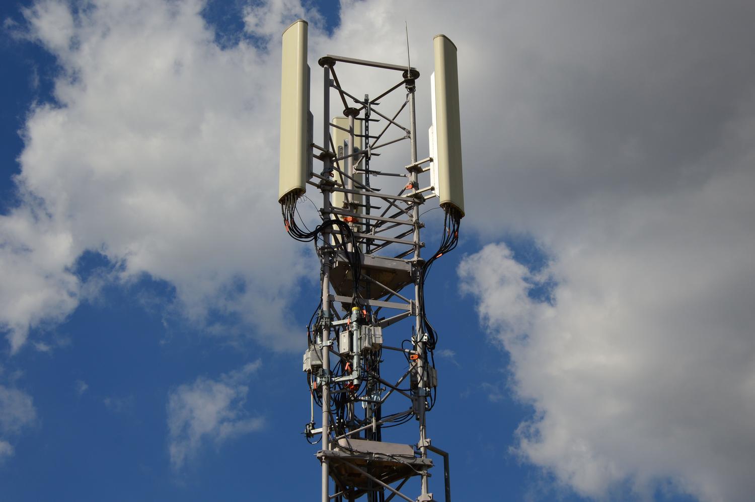Torre de telefonía móvil bajo un cielo azul, ilustrando la conectividad global y las redes 4G LTE mencionadas en las especificaciones.