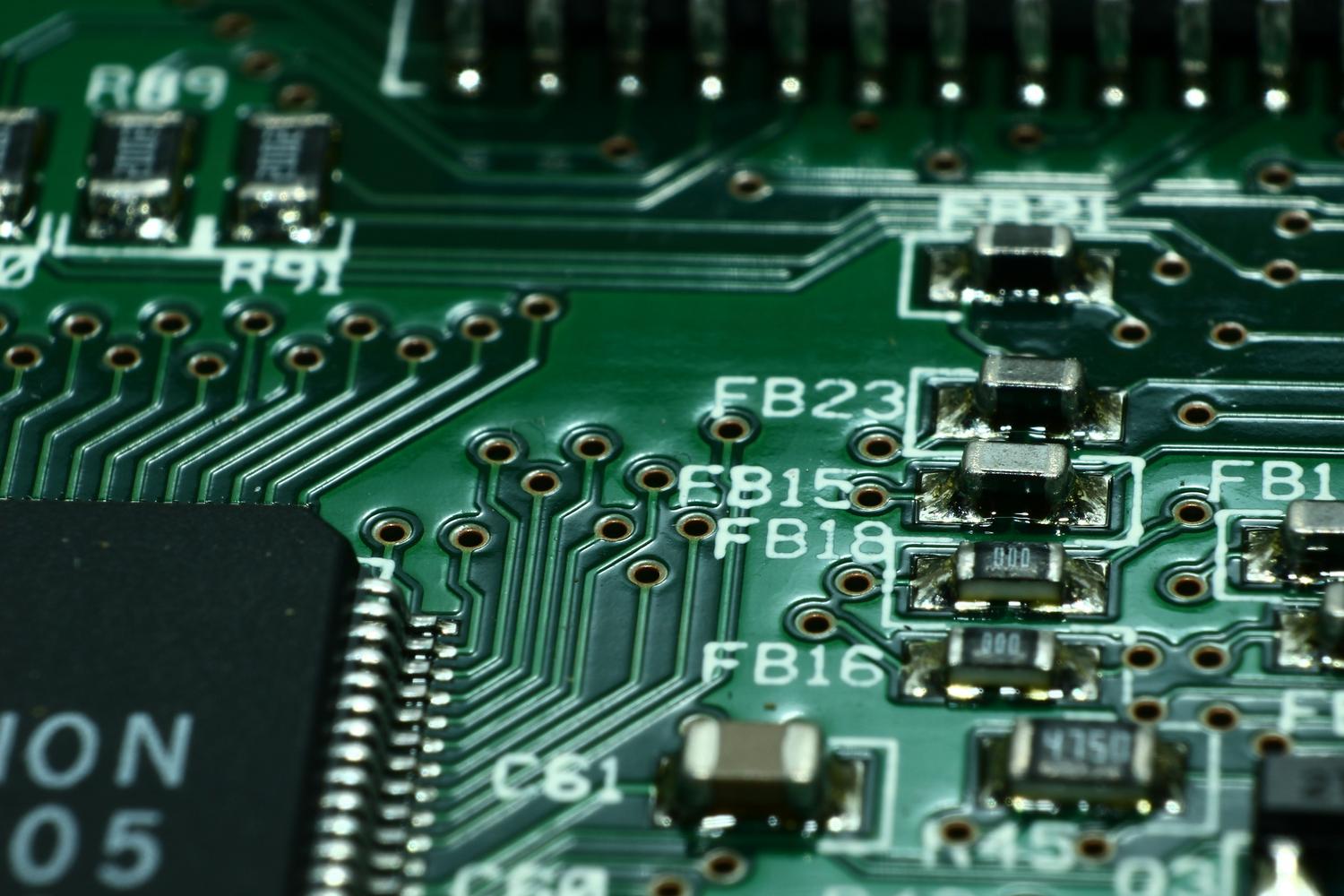 Vista macro de una placa de circuito impreso verde con microchips y componentes electrónicos detallados.