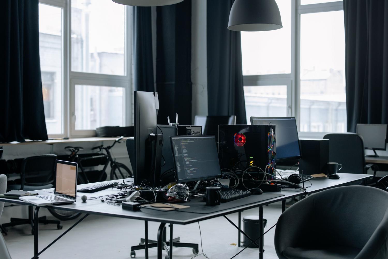 Espacio de trabajo moderno con múltiples monitores y torres de alta potencia para desarrollo de software.