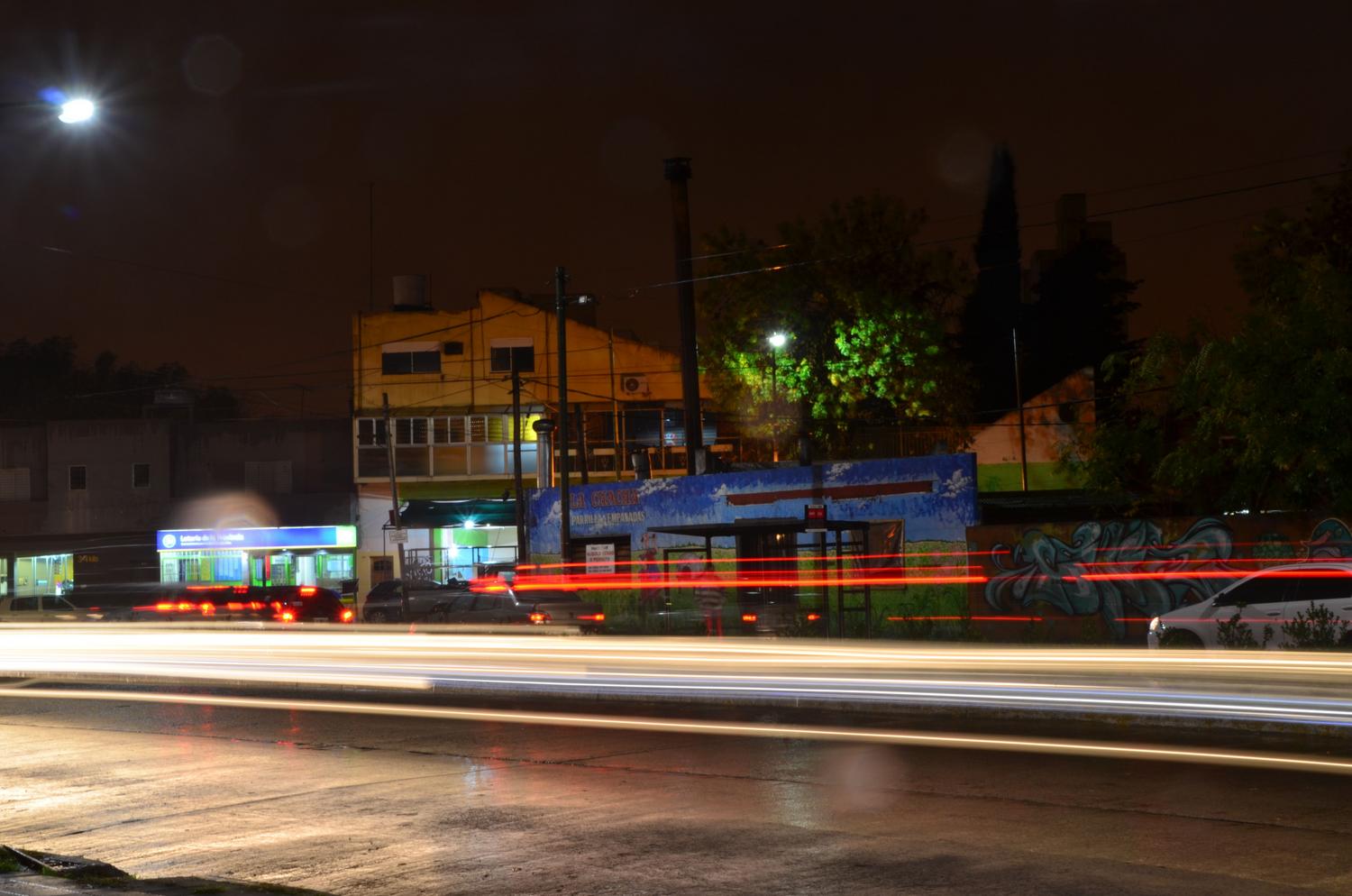 Fotografía de larga exposición nocturna en una ciudad con estelas de luz de coches en movimiento.