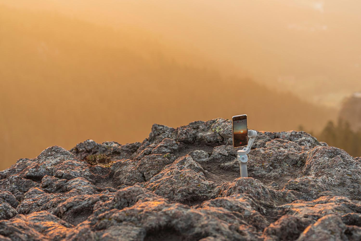 Smartphone montado en un gimbal capturando la luz de la hora dorada durante un amanecer en un paisaje natural. Smartphone montado en un gimbal capturando la luz de la hora dorada durante un amanecer en un paisaje natural.