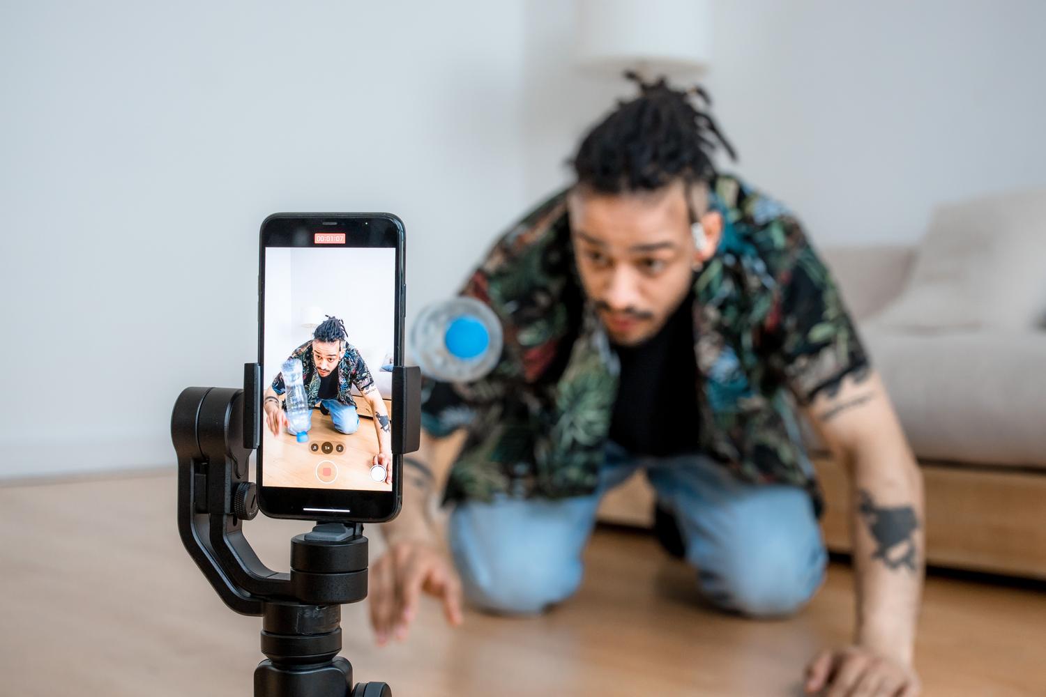 Hombre utilizando un estabilizador gimbal con su smartphone para grabar contenido fluido y profesional en interiores.