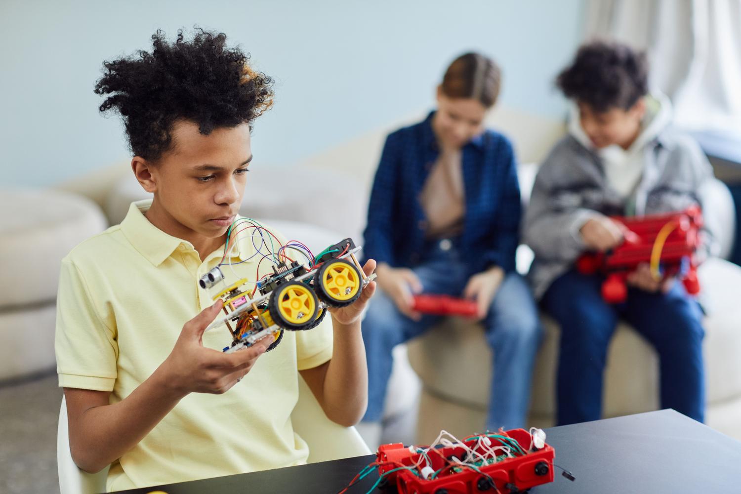 Grupo de niños trabajando en equipo para construir coches robóticos, ejemplificando la metodología de aprender haciendo.