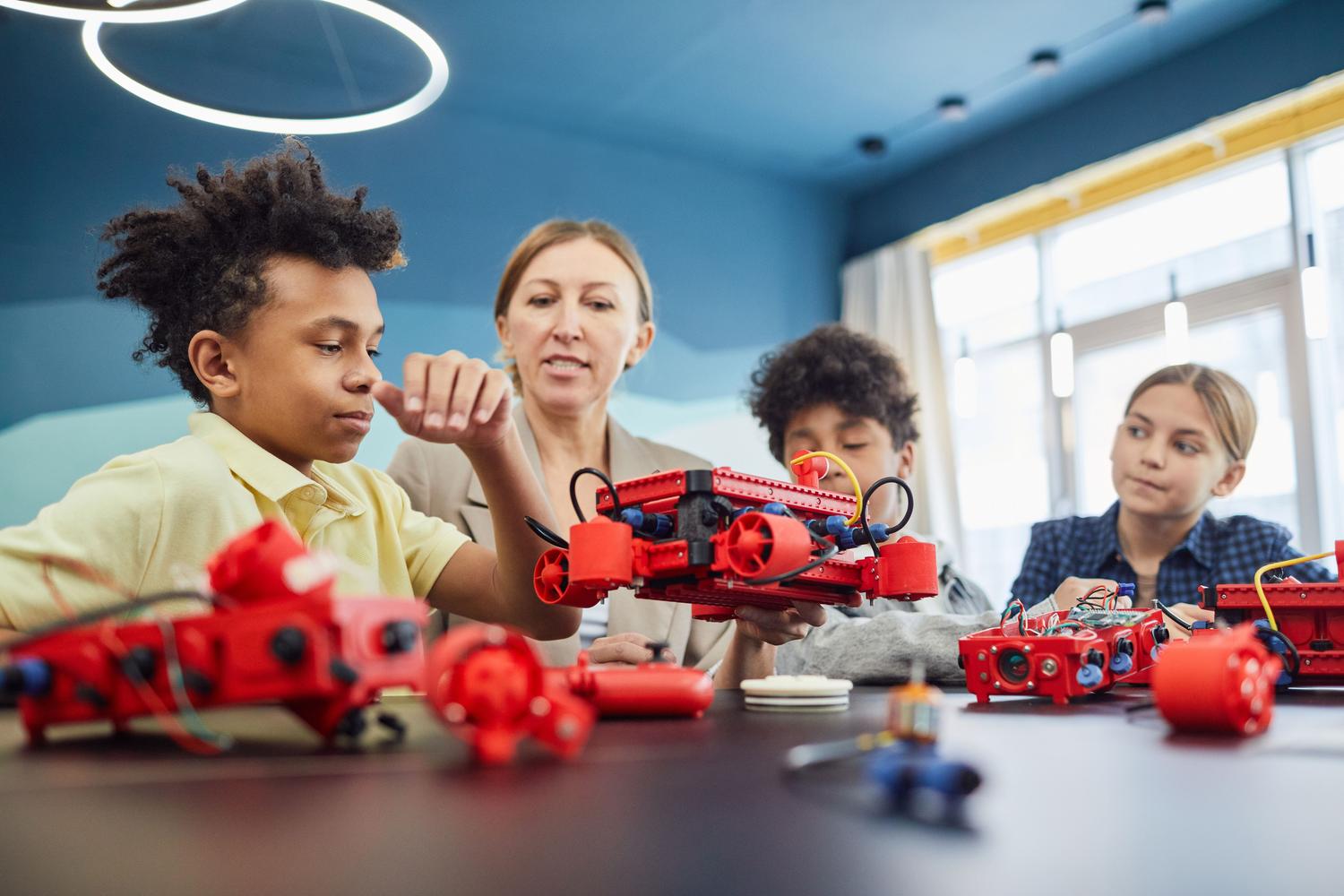 Una profesora y sus alumnos colaborando en la construcción de robots en un aula moderna de tecnología.