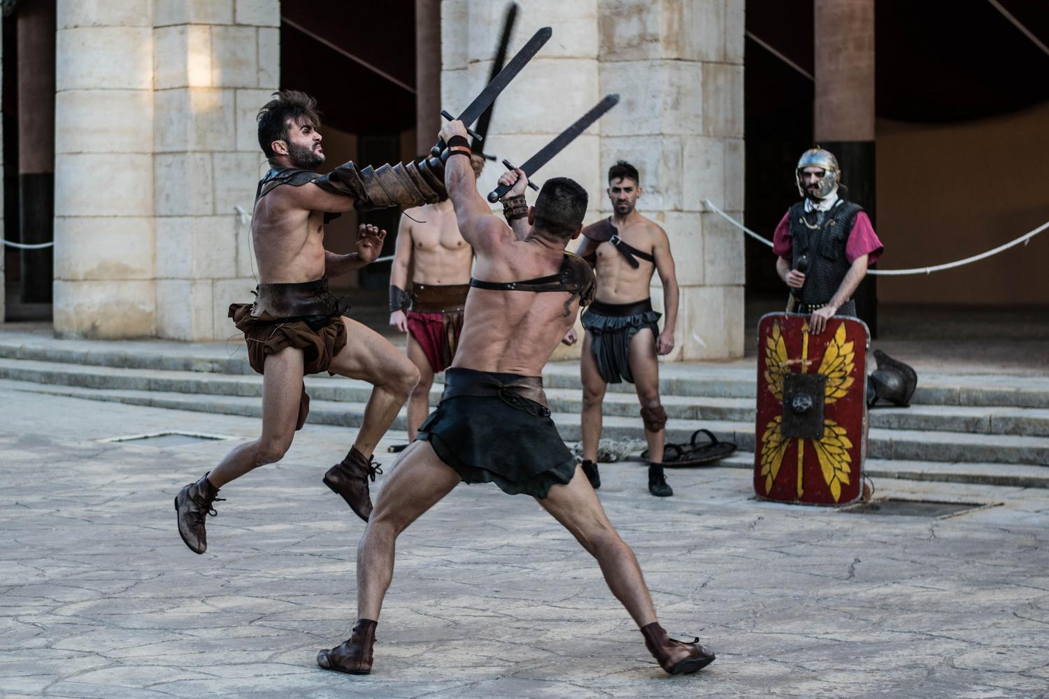Combate intenso de gladiadores con espadas en una arena, reflejando la acción frenética del juego.