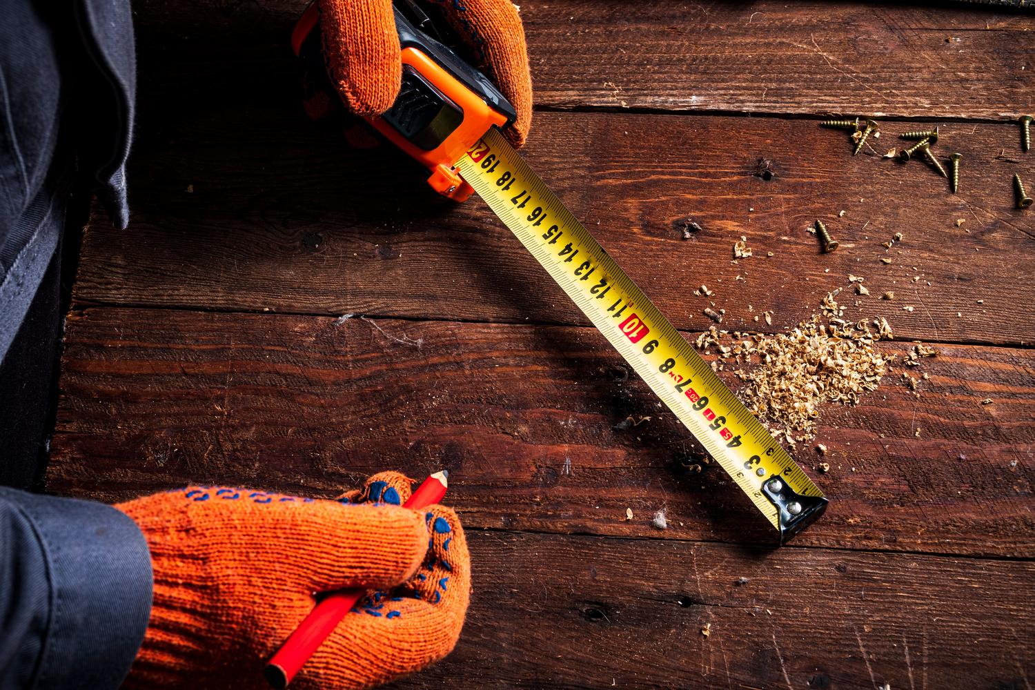 Primer plano de una cinta métrica tradicional sobre madera, representando el método de medición manual clásico.