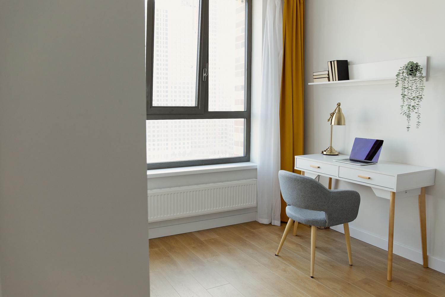 Escritorio compacto y sencillo en una habitación iluminada, ideal para teletrabajo en espacios pequeños.