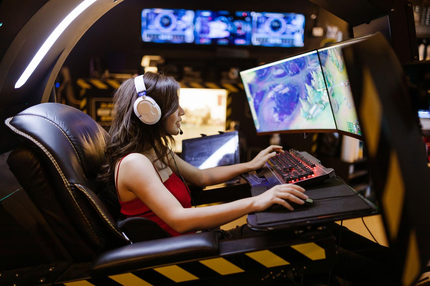 Jugadora concentrada en un entorno de gaming inmersivo con doble monitor curvo y configuración tipo cockpit.