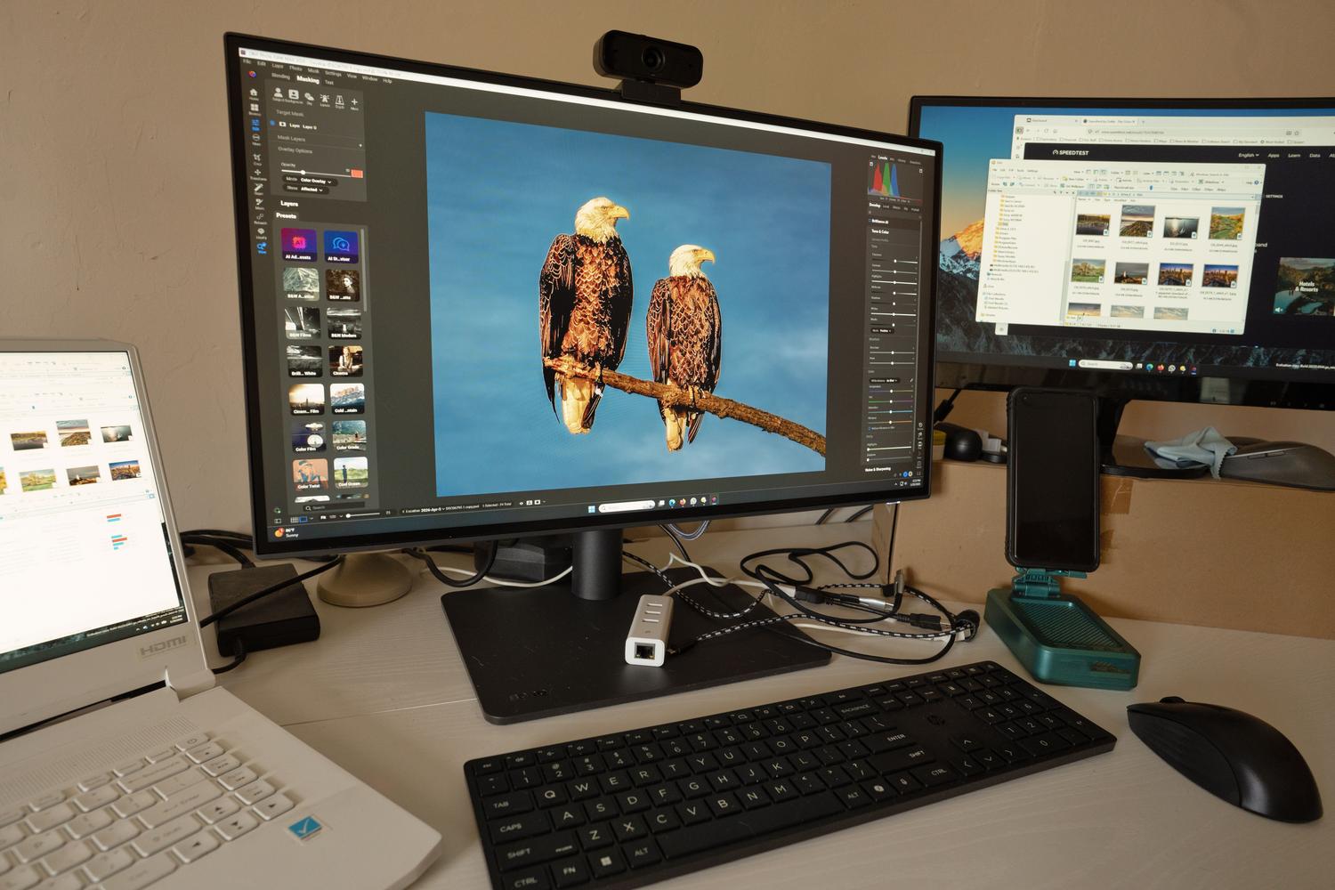 Professional workspace for photo editing with multiple high-resolution monitors displaying detailed wildlife photography.
