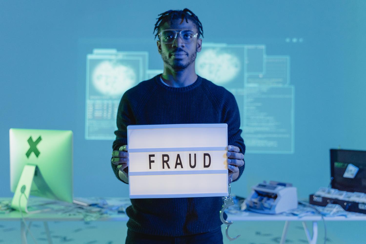 Representación conceptual de fraude digital con un letrero de 'FRAUD' y equipos informáticos, simbolizando las amenazas de ciberseguridad.