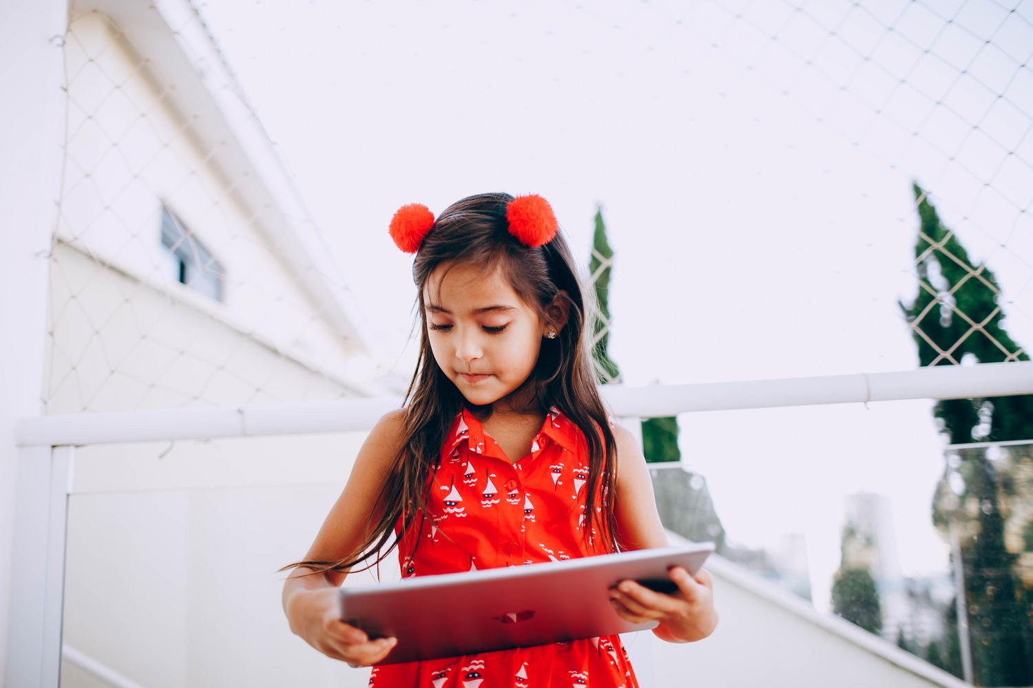 Niña utilizando una tablet en un entorno doméstico seguro, representación genérica de un menor navegando por internet.