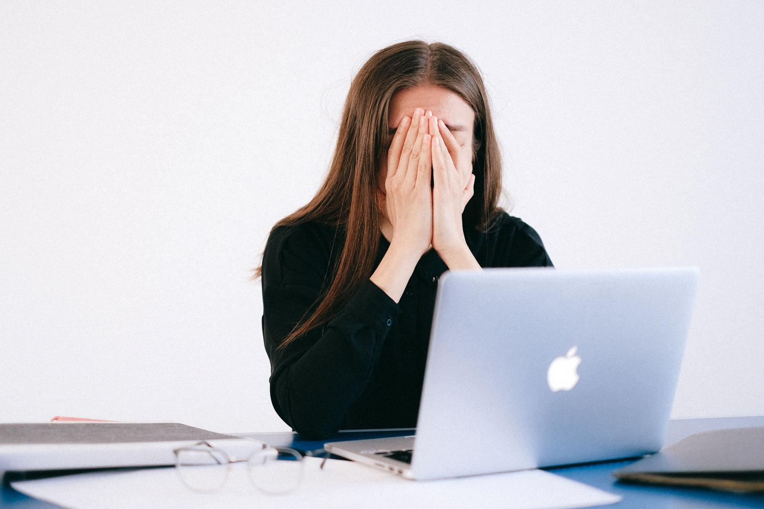 Profesional de TI sintiéndose abrumada y estresada frente a su ordenador, ilustrando la crisis de burnout en el puesto de CISO.