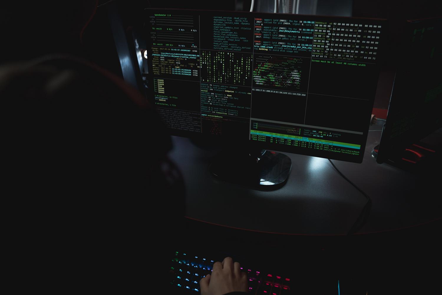 Centro de operaciones de seguridad con múltiples monitores mostrando código, simbolizando el blindaje técnico y la monitorización de amenazas.