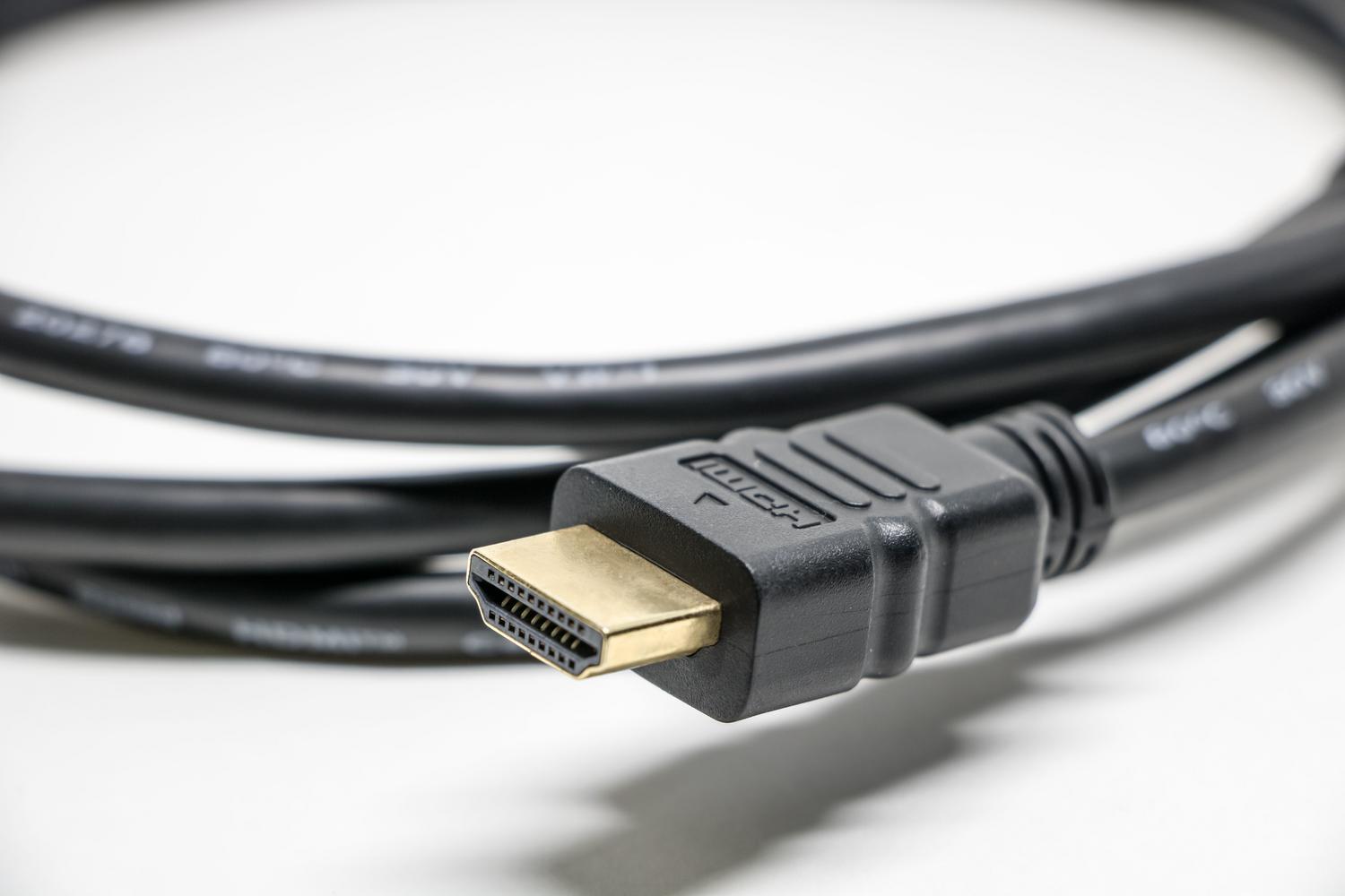 Primer plano detallado de un cable HDMI con conectores dorados sobre fondo blanco, ideal para ilustrar la conexión física de alta calidad.
